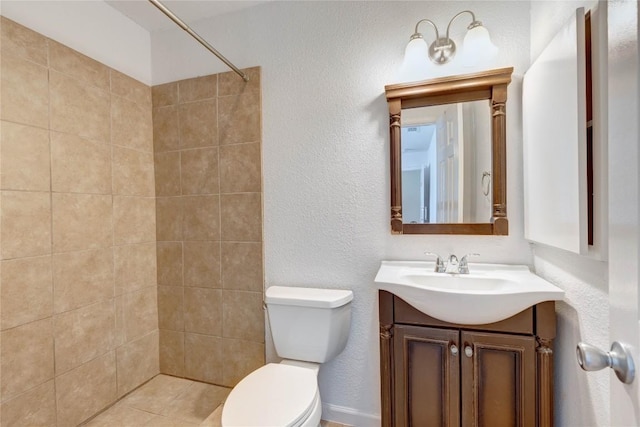 bathroom featuring a tile shower, vanity, and toilet