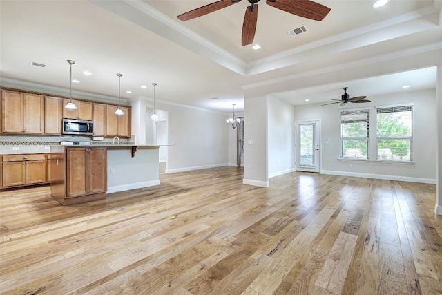 kitchen with hanging light fixtures, ceiling fan with notable chandelier, light hardwood / wood-style floors, and crown molding