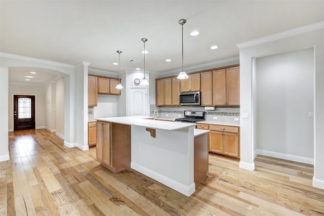 kitchen with stainless steel appliances, light hardwood / wood-style floors, a kitchen island with sink, and crown molding