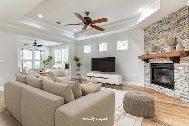 living room featuring a stone fireplace, light hardwood / wood-style floors, and ceiling fan