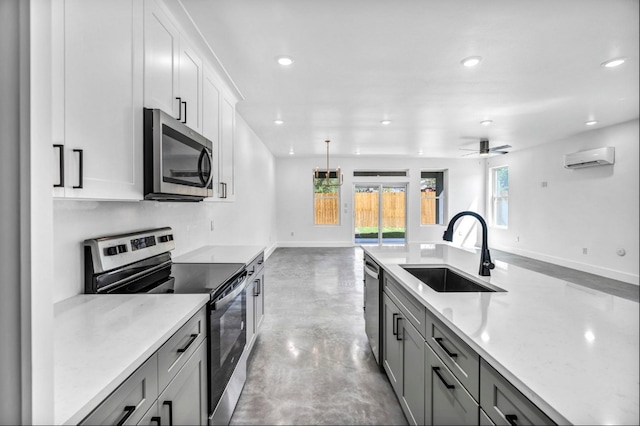 kitchen with appliances with stainless steel finishes, light stone counters, sink, ceiling fan, and pendant lighting