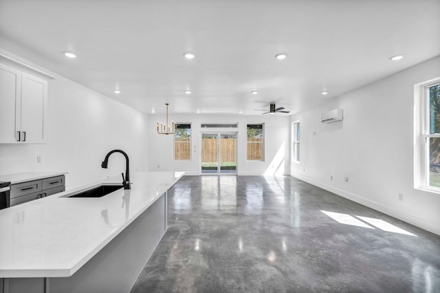 kitchen with plenty of natural light, concrete floors, sink, and ceiling fan with notable chandelier