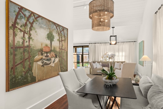 dining room featuring a notable chandelier, high vaulted ceiling, dark wood-type flooring, and baseboards