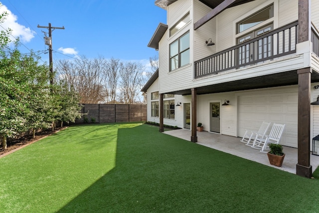 view of yard with a patio area, a balcony, fence, and a garage