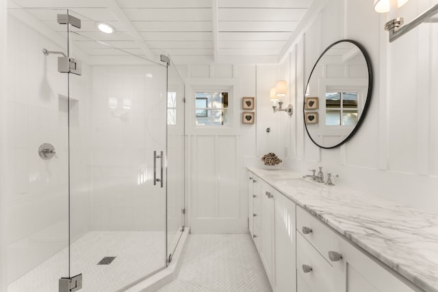 bathroom featuring a shower with shower door and vanity