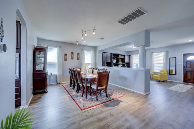 dining space featuring a wealth of natural light, hardwood / wood-style floors, and ornate columns