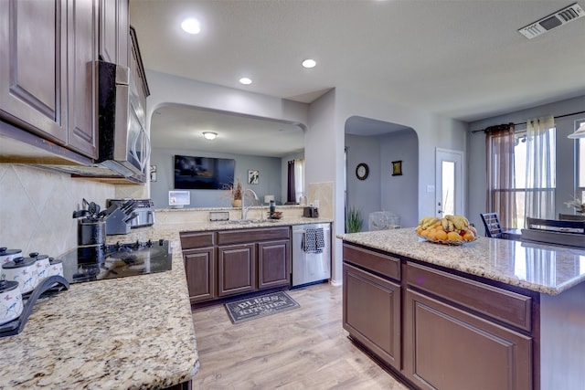 kitchen featuring a center island, stainless steel appliances, light stone countertops, and light hardwood / wood-style floors