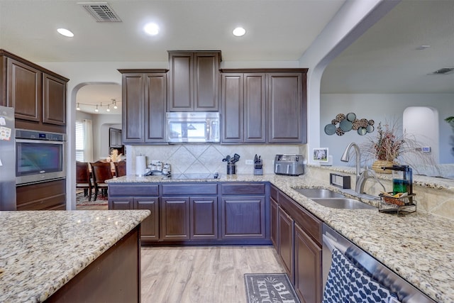 kitchen featuring light hardwood / wood-style flooring, light stone counters, sink, appliances with stainless steel finishes, and dark brown cabinetry