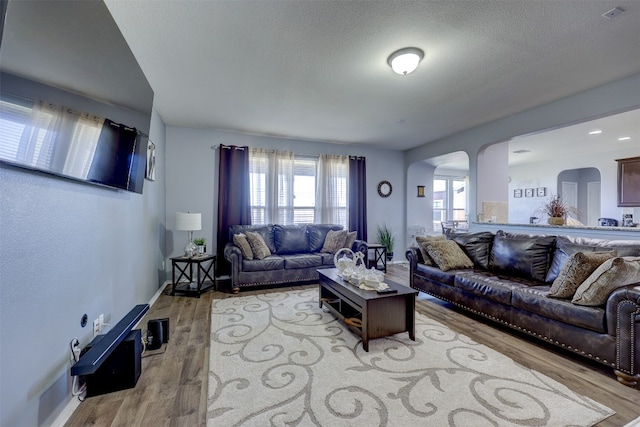 living room with light wood-type flooring and a textured ceiling