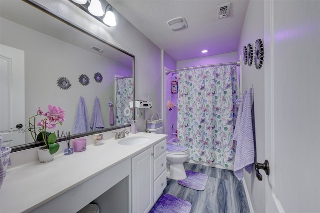 bathroom featuring toilet, walk in shower, vanity, a textured ceiling, and hardwood / wood-style flooring