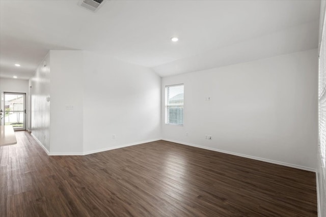 empty room featuring plenty of natural light, dark hardwood / wood-style flooring, and vaulted ceiling