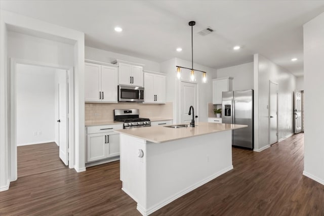 kitchen with dark hardwood / wood-style floors, appliances with stainless steel finishes, an island with sink, sink, and white cabinetry