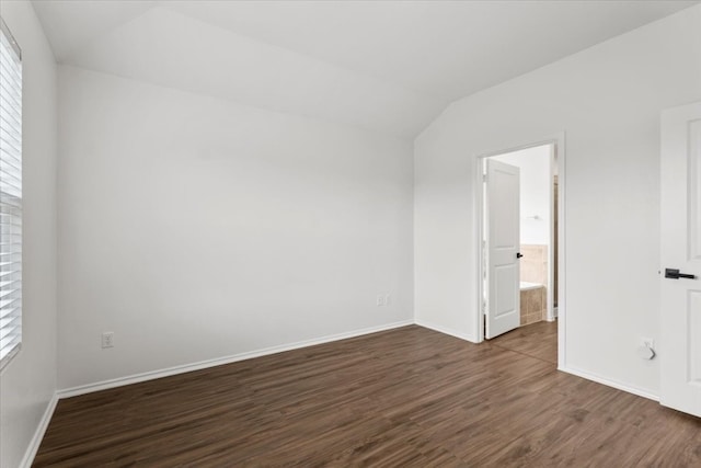 unfurnished bedroom with vaulted ceiling, ensuite bathroom, and dark hardwood / wood-style floors