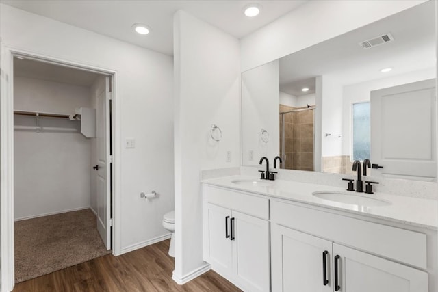 bathroom with tiled shower, vanity, toilet, and hardwood / wood-style floors