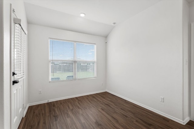 empty room with dark wood-type flooring and lofted ceiling