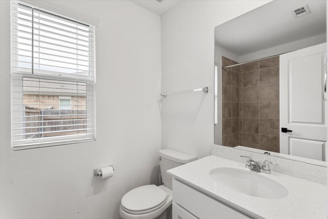 bathroom with vanity, toilet, and a tile shower