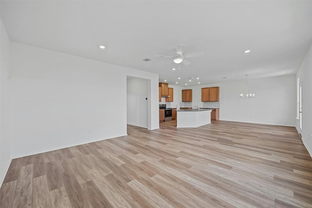 unfurnished living room with ceiling fan with notable chandelier and light hardwood / wood-style floors