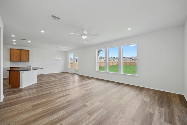 213 Skipping Stone Run, Georgetown, TX 78628 - unfurnished living room with a chandelier, ceiling fan, light wood-style floors, and recessed lighting