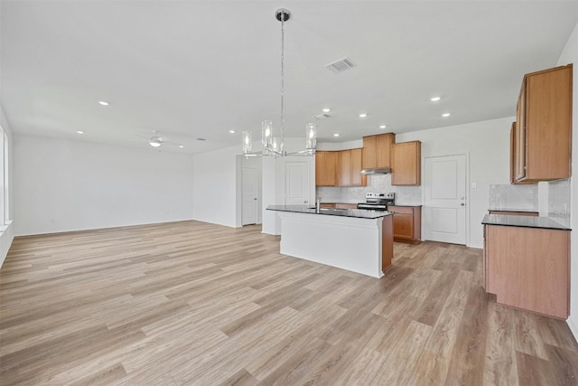 kitchen featuring stainless steel electric stove, tasteful backsplash, a center island with sink, and light hardwood / wood-style flooring