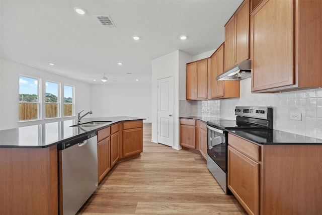 213 Skipping Stone Run, Georgetown, TX 78628 - kitchen with appliances with stainless steel finishes, under cabinet range hood, light wood-type flooring, an island with sink, and decorative backsplash