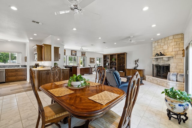 dining area featuring ceiling fan, plenty of natural light, and a fireplace