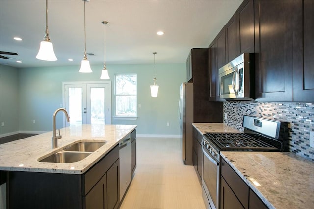 kitchen with a center island with sink, a sink, stainless steel appliances, french doors, and tasteful backsplash