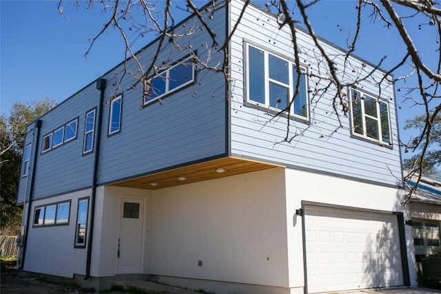 back of property featuring an attached garage and stucco siding