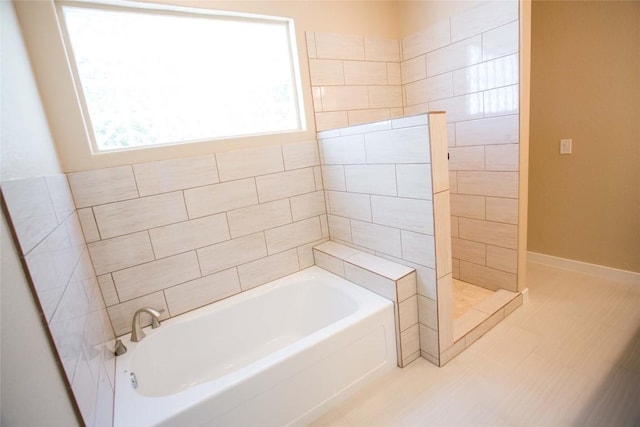 full bath featuring baseboards, a bath, and a walk in shower