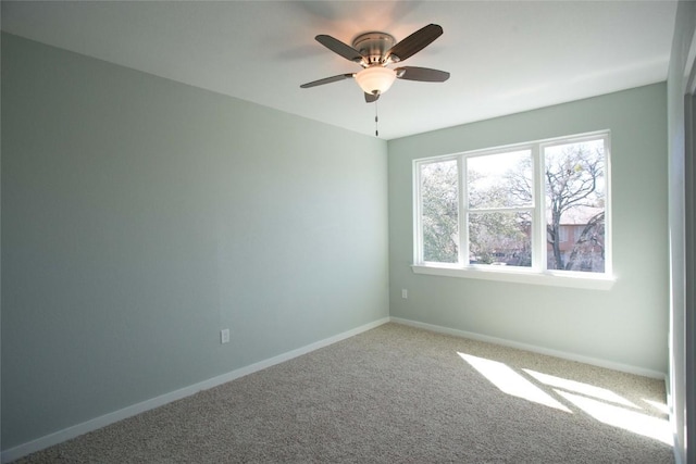 carpeted empty room featuring ceiling fan and baseboards