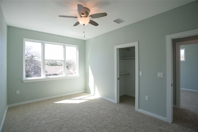 unfurnished bedroom featuring a walk in closet, carpet flooring, visible vents, and baseboards