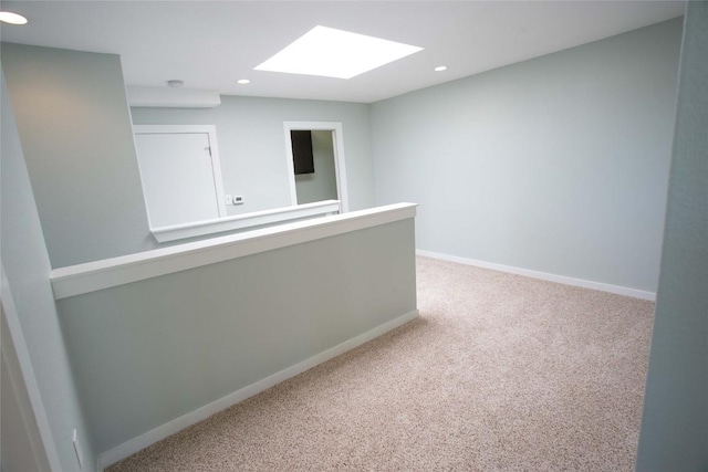 spare room with a skylight, carpet flooring, recessed lighting, and baseboards