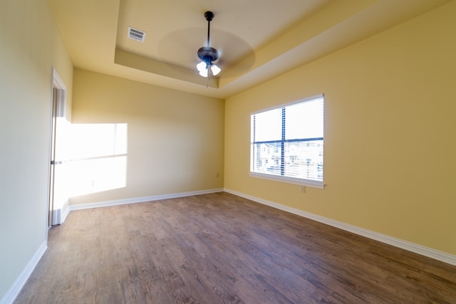 spare room with a tray ceiling, ceiling fan, and hardwood / wood-style floors