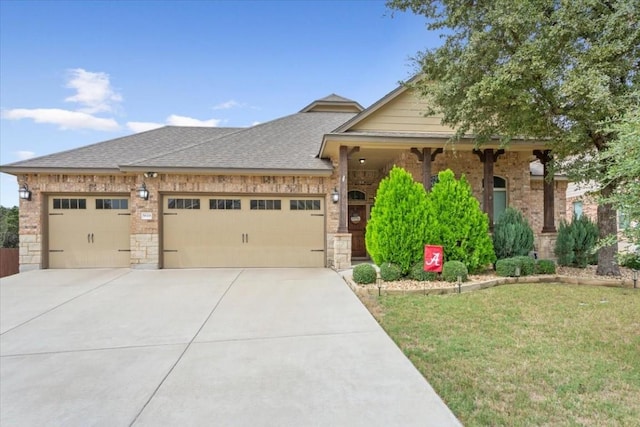 view of front of house with a front yard, an attached garage, a shingled roof, concrete driveway, and brick siding