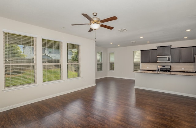 unfurnished living room with a wealth of natural light, ceiling fan, and dark hardwood / wood-style floors