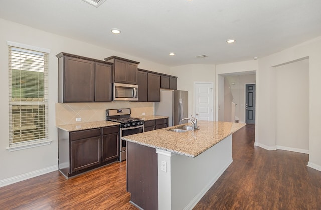 kitchen with an island with sink, dark wood-type flooring, sink, and appliances with stainless steel finishes