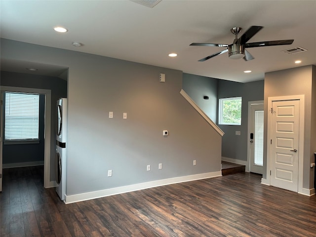 empty room featuring ceiling fan, dark hardwood / wood-style floors, and stacked washer / dryer