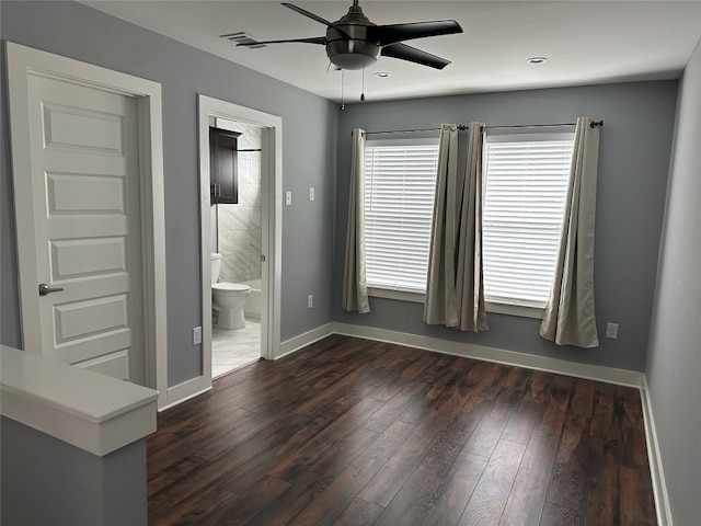 unfurnished bedroom featuring dark wood-type flooring, ceiling fan, and connected bathroom