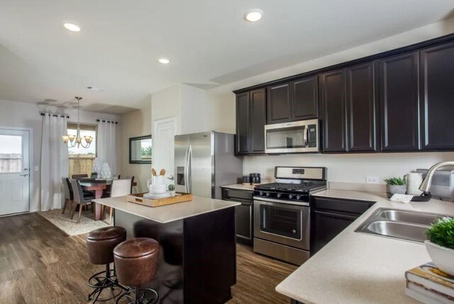 kitchen with dark hardwood / wood-style flooring, pendant lighting, a center island, stainless steel appliances, and sink