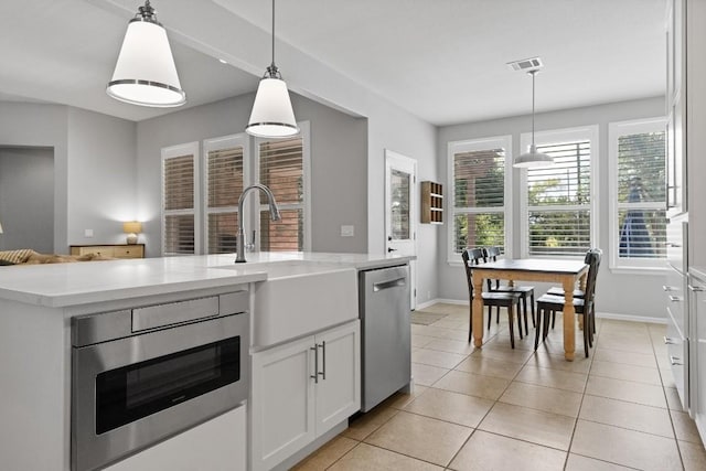 kitchen with white cabinetry, hanging light fixtures, stainless steel dishwasher, and sink