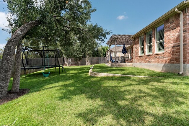 view of yard with a pergola and a trampoline