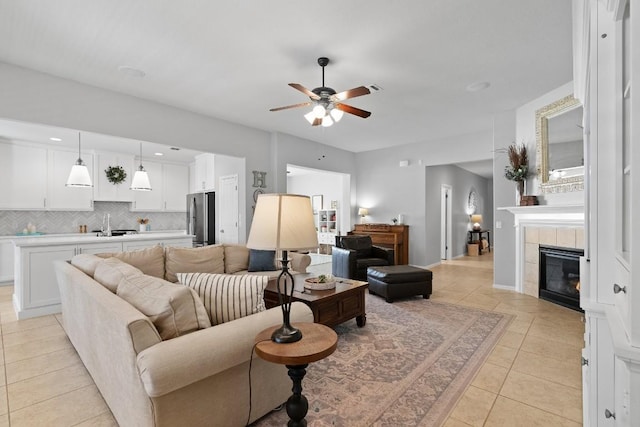 tiled living room featuring ceiling fan, sink, and a fireplace