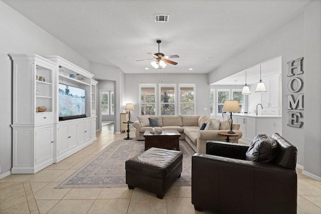 living room featuring ceiling fan, sink, light tile patterned floors, and a healthy amount of sunlight