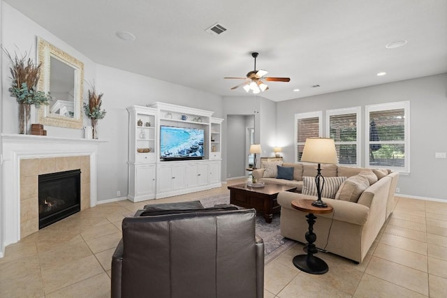 tiled living room with ceiling fan and a tiled fireplace