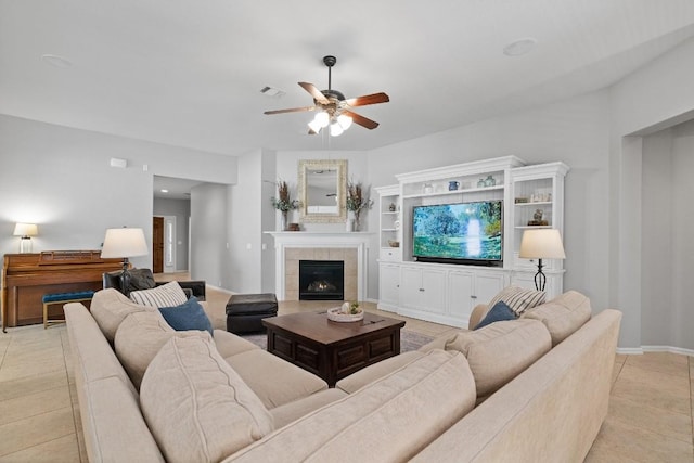 tiled living room featuring ceiling fan and a tile fireplace