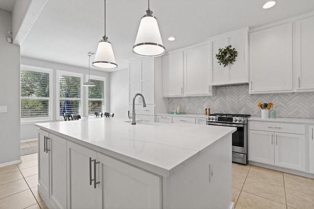 kitchen featuring white cabinets, a kitchen island with sink, stainless steel stove, and decorative light fixtures