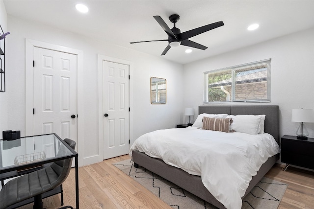 bedroom featuring multiple closets, ceiling fan, and light wood-type flooring