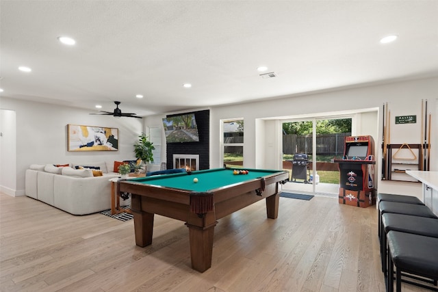 recreation room with ceiling fan, a large fireplace, billiards, and light wood-type flooring