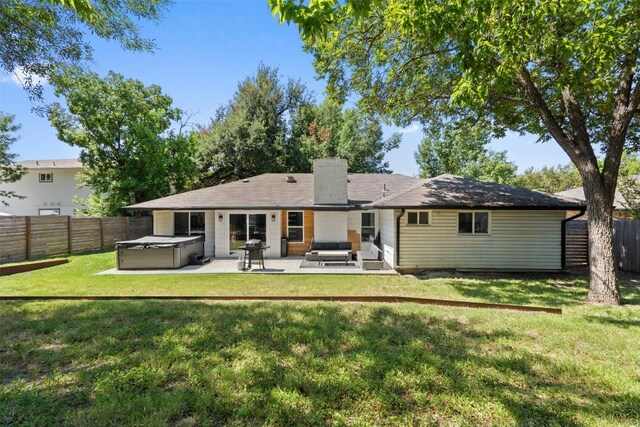 rear view of property featuring a patio area, an outdoor living space, a yard, and a hot tub