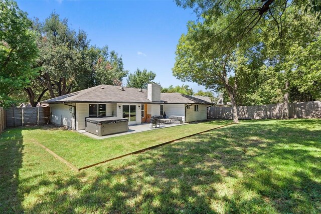 rear view of house with outdoor lounge area, a hot tub, a patio area, and a lawn