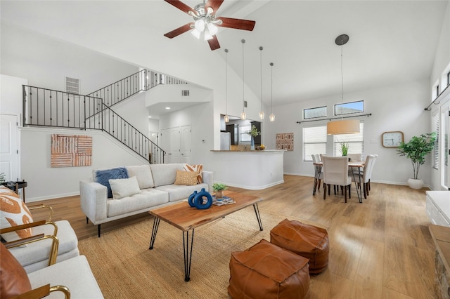 living room with light hardwood / wood-style flooring, high vaulted ceiling, and ceiling fan